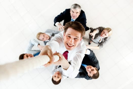Image of businessman ascending up the rope with business people trying to stop him