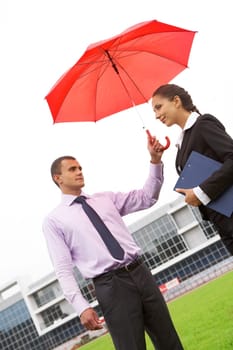 Portrait of handsome man holding red umbrella above female head