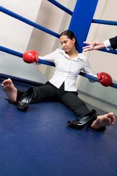Portrait of tired businesswoman in boxing gloves sleeping on boxing ring