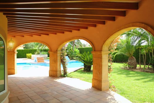 colonnade archs house in yellow on blue swimming pool garden