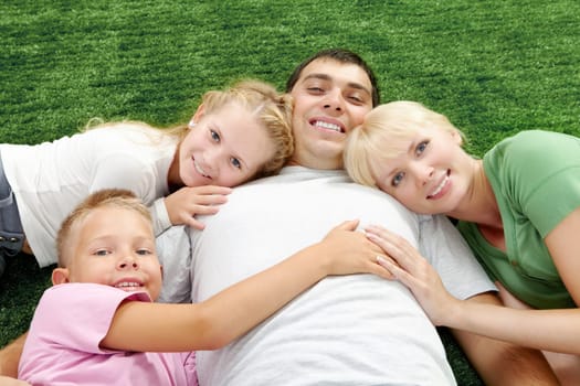 Image of happy parents with their kids lying on grass