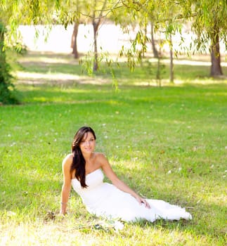 bride woman sitting in park grass with white rose