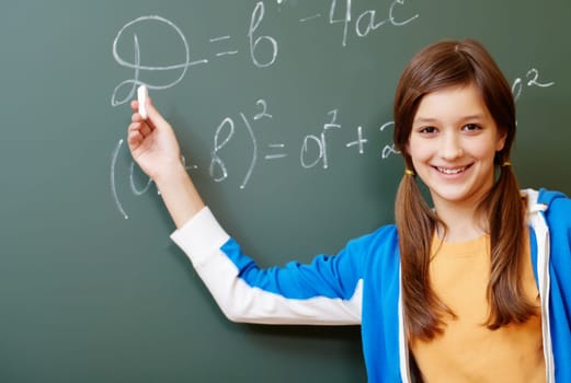 Confident student pointing at formula on blackboard during algebra lesson