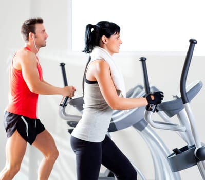 man and woman with elliptical cross trainer in sport fitness gym club
