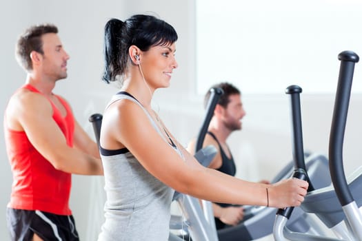man and woman with elliptical cross trainer in sport fitness gym club
