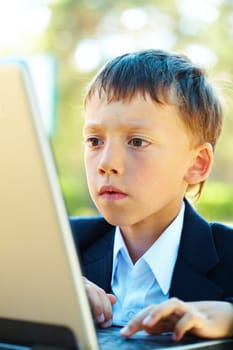 Portrait of smart boy working with laptop with attention