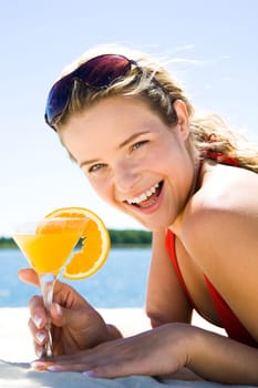 Photo of beautiful woman holding a orange cocktail and laughing