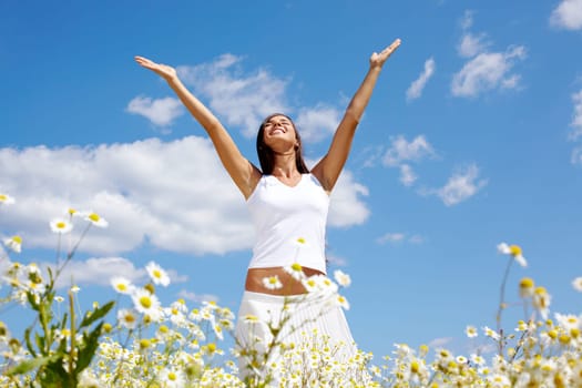 Image of happy female standing with raised arms on summer day