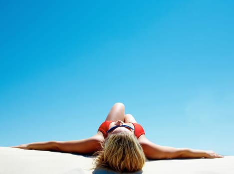 View of beautiful woman lying on the sand getting pleasure