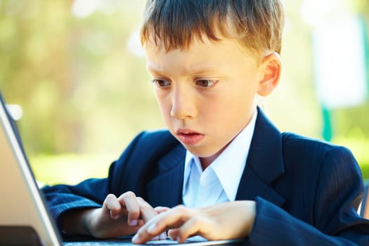 Portrait of smart boy working with laptop with attention