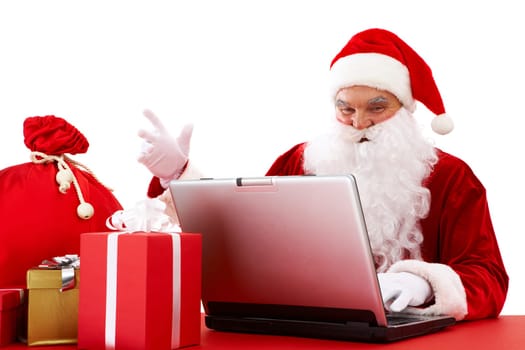 Portrait of Santa Claus in front of laptop with gifts near by