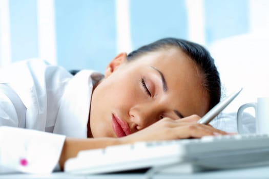 Image of young businesswoman sleeping on workplace with her head on keyboard
