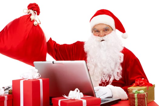 Portrait of Santa Claus in front of laptop with gifts near by