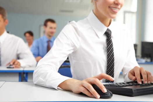 Image of female hand on mouse while typing on keyboard in a working environment