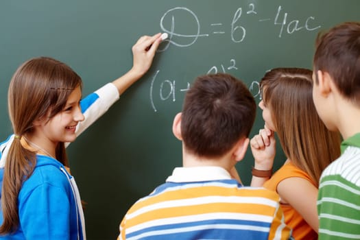 Confident student explaining formula on blackboard during algebra lesson