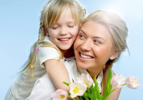 Portrait of little girl loving mother holding her and tulips