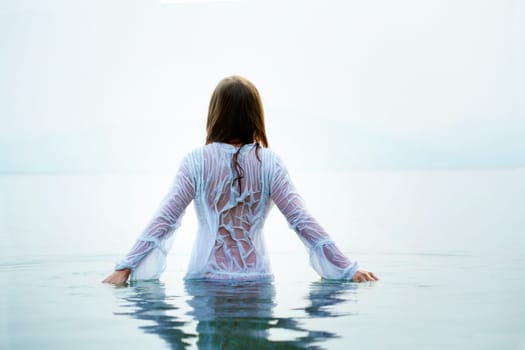 Rear view of beautiful female bathing in blue water