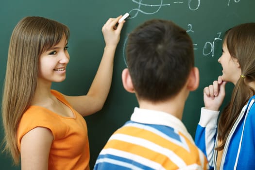 Confident student explaining formula on blackboard during algebra lesson