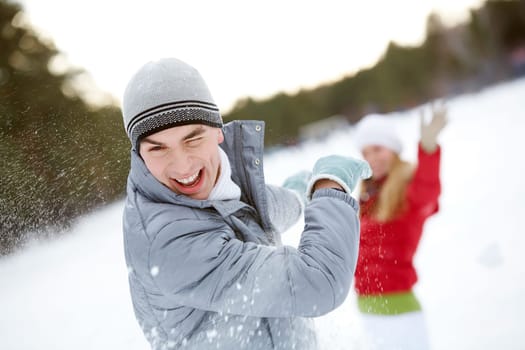 Image of attractive young man laughing during snowball play