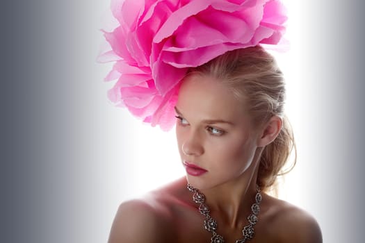 Gorgeous woman with pink flower on head looking aside