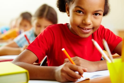 Portrait of cute girl drawing with crayons at lesson