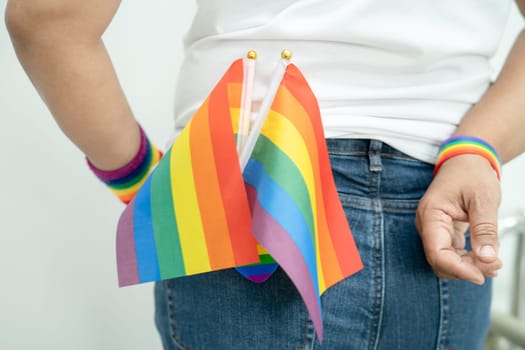 Woman holding LGBT rainbow colorful flag, symbol of lesbian, gay, bisexual, transgender, human rights, tolerance and peace.