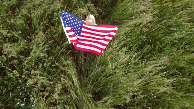 full length blond Woman holding American Flag in trees shadow of sunlight Back view cute blondy girl run on fresh green grass texture.