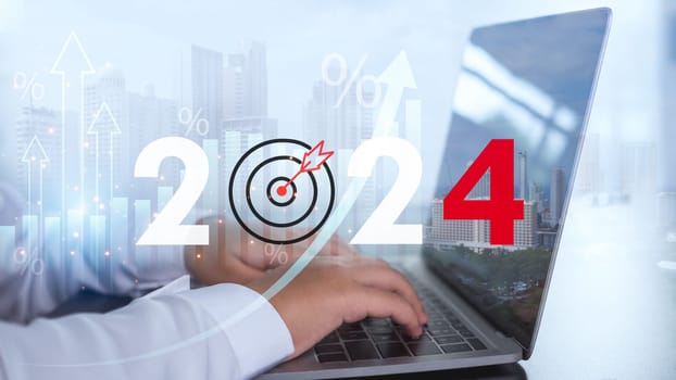 Businessman is using a computer and showing the letters 2024 representing setting goals for the year 2024 and the concept of starting a business along with financial planning and business strategy.
