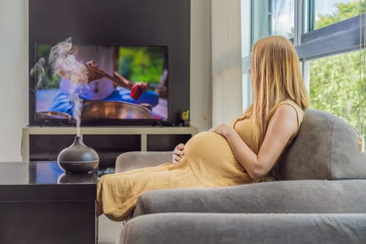 A blissful pregnant woman immerses in relaxation, savoring the soothing aroma from a diffuser while indulging in a calming TV video, embracing tranquility during her pregnant journey.