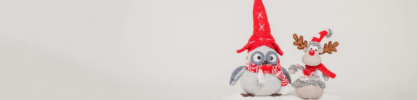 A toy figure of an owl and deer in a red hat. Isolated on a grey background. christmas decorations