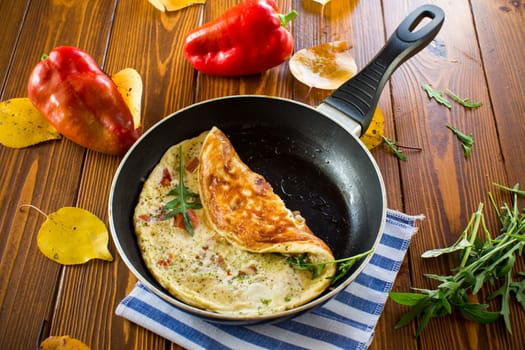 Fried omelets with various autumn vegetables in a frying pan on a wooden table. Autumn recipes.