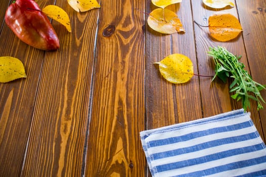 wooden background with empty clean space in the center, autumn foliage, autumn vegetables.