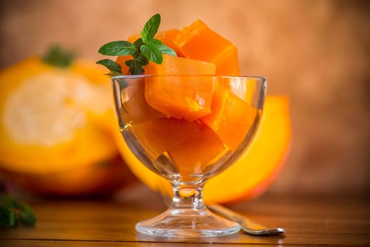 Prepared sweet pumpkin marmalade in a glass bowl on a wooden table. Autumn recipes.