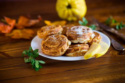 Cooked fried round pancakes with quince filling, cute pancakes with a smile, autumn recipes, on a wooden table