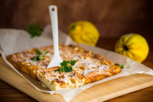 prepared curd semolina pie with quince inside and covered with powdered sugar on a wooden board.