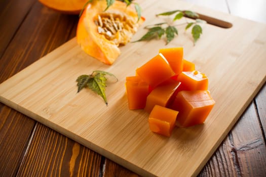 Prepared sweet pumpkin marmalade on a wooden table. Autumn recipes.