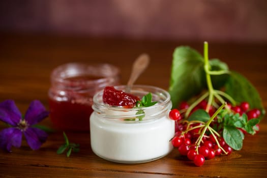 Prepared homemade yogurt with viburnum jam and viburnum on a wooden table.