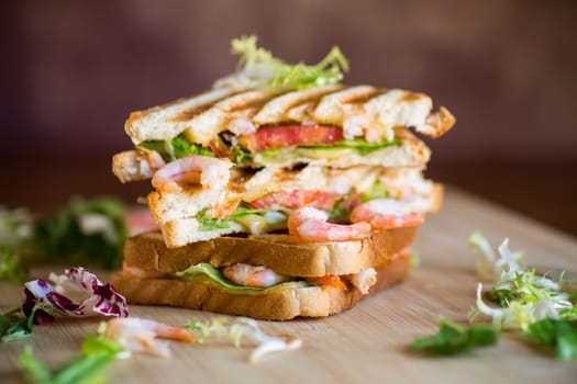 sandwich with lettuce and shrimp on a wooden board