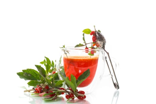 Prepared hot drink from ripe goji berries in a glass cup isolated on white background..