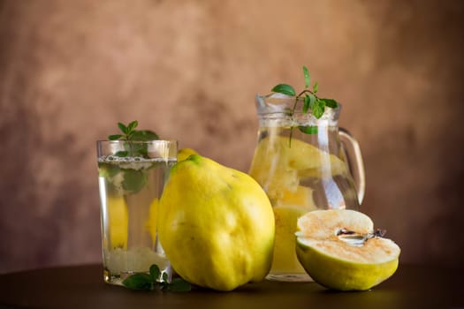 Prepared compote from ripe natural autumn quince, in a glass glass and decanter on a dark wooden table.