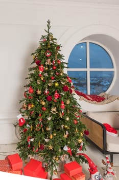 Big christmas tree decorated with beautiful red baubles at home. Copy space.