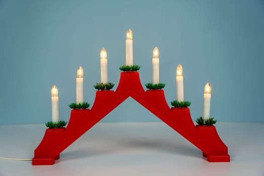 Traditional Christmas candle holder with seven candles on a blue winter background. Christmas candle bridge with seven candle lights. decoration for the celebration of the New Year