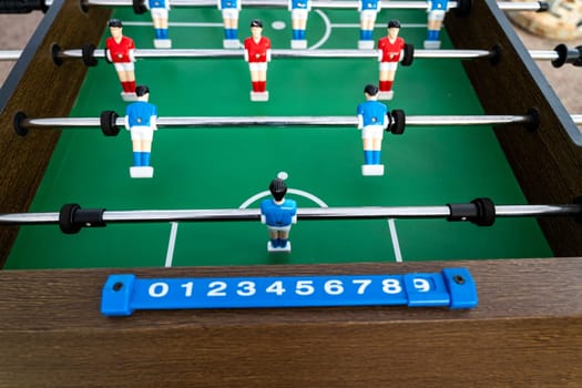 Table football. Close-up of figures of plastic players in a football match. red and blue players kick the ball.