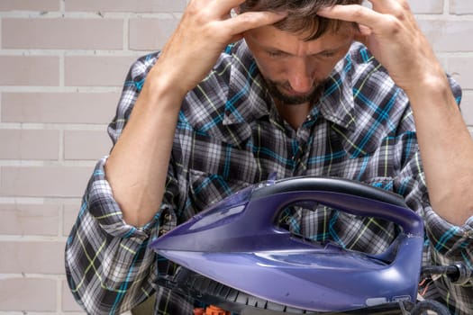 a mountain master repairs an electric iron. the repairman doesn't know how to fix it. Frustrated master. Disassembled electric iron.