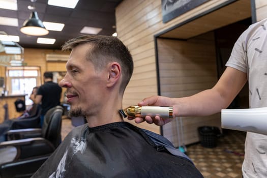 a professional hairdresser cuts a man's hair. visit to the barber shop. hair cutting for the client. creating a hairstyle in a beauty salon. Men's haircut in a barbershop.