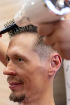 a professional hairdresser cuts a man's hair. visit to the barber shop. hair cutting for the client. creating a hairstyle in a beauty salon. Men's haircut in a barbershop.