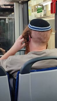 red-haired Jewish guy in a kippah ri ftdes on a bus, sits with his back turned, people, young man. High quality photo