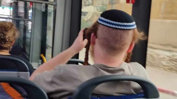red-haired Jewish guy in a kippah ri ftdes on a bus, sits with his back turned, people, young man. High quality photo