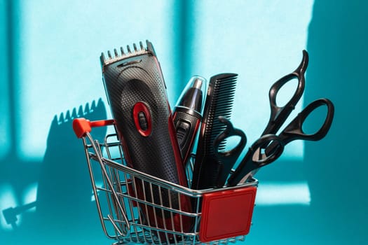 Hair clippers, two pairs of scissors and one comb lie in a mini basket on a blue background, close-up side view. The concept of hairdressing and shopping.