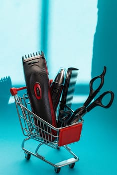 Hair clippers, two pairs of scissors and one comb lie in a mini basket on a blue background, close-up side view. The concept of hairdressing and shopping.